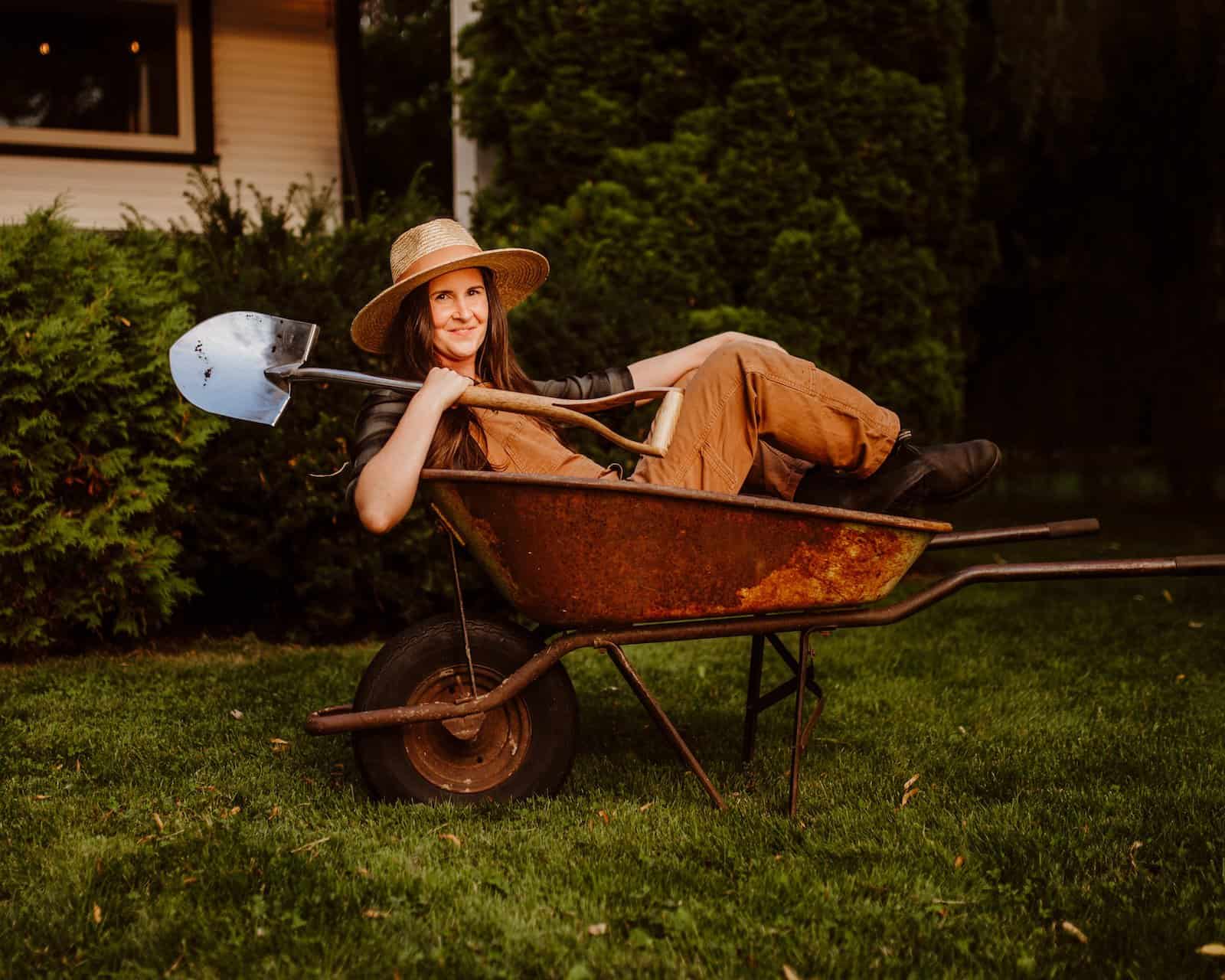 Gardener holding digging spade in wheelbarrow